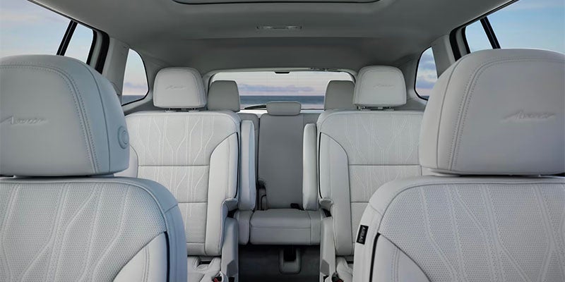 Spacious luxury vehicle interior featuring white leather seats and a modern three-row cabin layout.