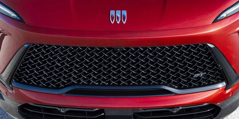 Close-up view of a red luxury SUV grille featuring a diamond-pattern mesh design and chrome accents.