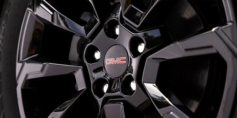 Close-up view of a GMC alloy wheel featuring a glossy black finish and branded center cap.