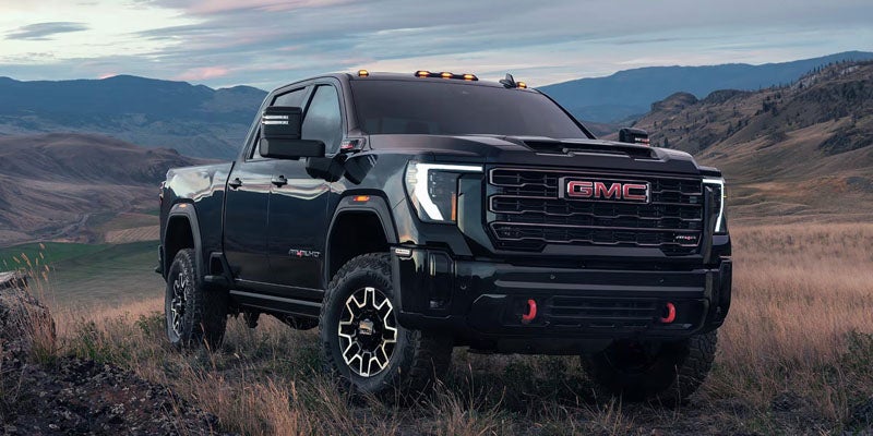 Black GMC pickup truck parked on a rugged landscape with mountains in the background.